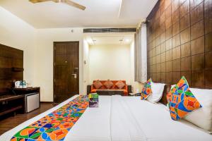 新德里FabHotel Aashraye的卧室配有一张带彩色枕头的大型白色床。