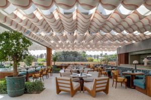 多哈The Ned Doha的屋顶下设有桌椅的餐厅