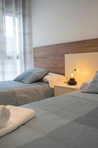 阿尔卡拉拉雷亚尔Deluxe Apartament Alcalá la Real的一间卧室设有两张床和一张桌子上的台灯。