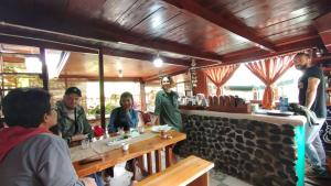 Kayu AroPelangi Guest House的一群坐在餐厅桌子上的人