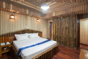 勃固KMA SHWE PYI BAGO Resort的木墙客房内的一张大床