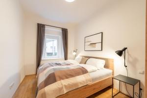 格拉茨Premium Apartments im Stadtzentrum的白色卧室配有床和桌子