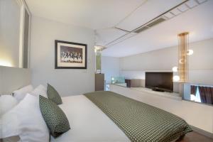 玛琅Lux Tychi Hotel的一间卧室配有一张床和一台平面电视