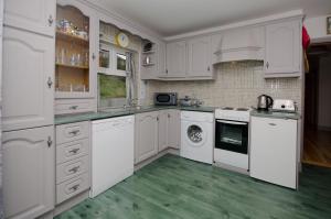 克利夫登Cottage 171 - Clifden的一间铺有绿色地板并配有白色橱柜的厨房