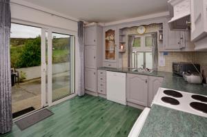 克利夫登Cottage 171 - Clifden的一间铺有绿色地板并配有白色橱柜的厨房