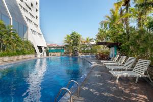 玛琅Lux Tychi Hotel的一座带躺椅的游泳池位于大楼旁