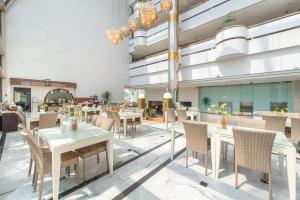 玛琅Lux Tychi Hotel的餐厅的 ⁇ 染,配有桌椅