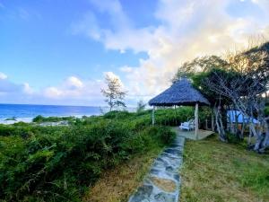瓦塔穆Watamu Beach Cottages的通往带凉亭和大海的海滩的路径
