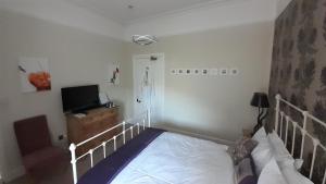 South KessockTrafford Bank Guest House的一间卧室配有一张床和一台平面电视