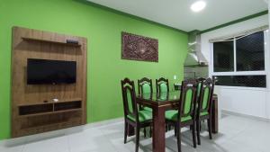 乌巴图巴Apartamento Resort Palmeiras 2 com 03 Quartos Ubatuba的一间拥有绿色墙壁和桌椅的用餐室