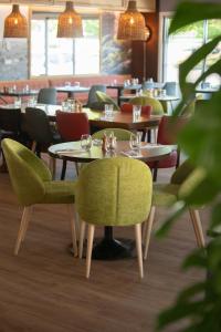 卡斯泰The Originals City, Hôtel Les Bruyères, Dax Nord (Inter-Hotel)的一间在房间内配有桌椅的餐厅