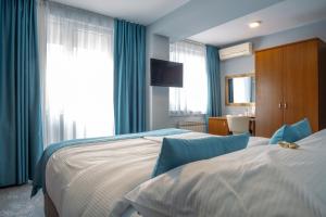 萨拉热窝Hotel Villa Harmony的两张位于酒店客房的床,配有蓝色窗帘
