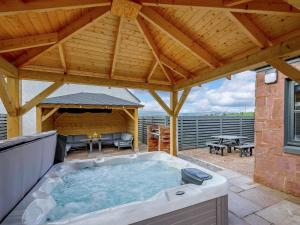 巴洛赫Westertonhill Lodge 8 Newbuild with Hot Tub Option的一个带木屋顶的庭院内的热水浴池
