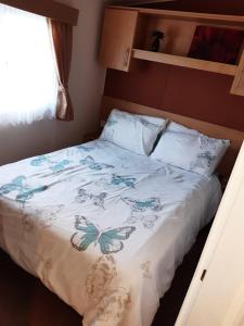 LincolnshireBUTLINS SKEGNESS, 3 Beds, Pet Friendly - The Paddock的一张带白色床罩的床,上面有蝴蝶