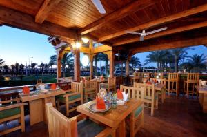 沙姆沙伊赫Jaz Sharm Dreams的餐厅拥有木桌和椅子,并种植了棕榈树。