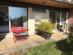 泽拉特Chez Isa, espace prive, 1ou 2 chambres, terrasse et jardin, entrée autonome, sdb et mini cuisine partagées entre les 2 chambres的房屋前方的庭院配有红色的桌椅