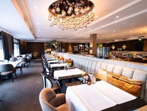 菲亚嫩Van der Valk Hotel Vianen - Utrecht的一间设有白色桌椅的餐厅和一间酒吧
