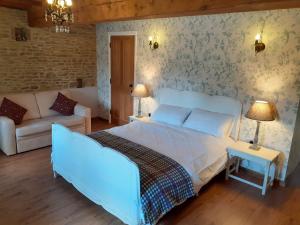 Ashton KeynesThe Byre North End Farm的卧室配有一张白色的大床和一张沙发。