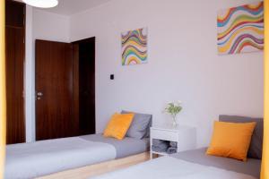 巴勒尔Baleal Surf Emotions的一间卧室设有两张床,墙上挂着色彩缤纷的画作