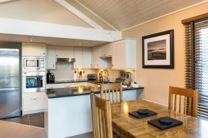 巴洛赫Cameron House Lodges的厨房配有白色橱柜和木桌