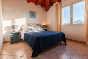 圣特奥多罗撒丁岛夏日丽卡普拉提公寓的一间卧室配有一张蓝色床罩和两个窗户。