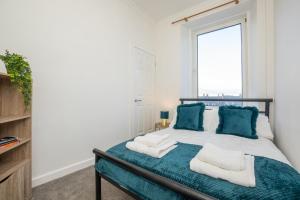 阿伯丁Brulee House - Luxury 2 Bed Apartment in Aberdeen Centre的一间卧室配有一张带蓝色枕头的床和一扇窗户。
