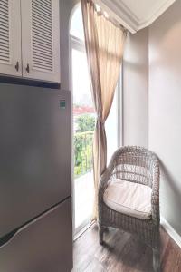 胡志明市HOME by FLATTO APARTMENT的厨房在窗户前配有藤椅