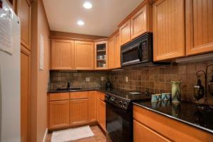 可可比奇Quiet Vista Del Mar 2 Bedroom Condo Beachfront Property的厨房配有木制橱柜和炉灶烤箱。