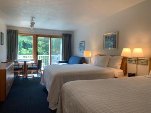 鱼溪AppleCreek Resort-Hotel & Suites的酒店客房带两张床和一张桌子以及椅子。