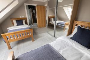 巴洛赫Westertonhill Lodge 5 Newbuild with Hot Tub Option的阁楼卧室配有两张床和镜子
