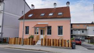 格拉茨Ferienwohnung Christa的一座粉红色的小房子,设有木栅栏