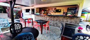 TemaeMOOREA - The Golden Reef Bungalow Moorea的餐厅内带红色椅子和桌子的酒吧