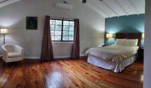 Santa ElenaSanta Cruz Cabins的卧室配有床、椅子和窗户。