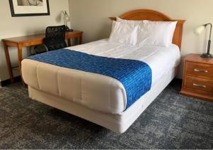 林垦Travelodge by Wyndham Lincoln Northeast的一张床位,位于酒店客房内,配有书桌和一张四柱床。