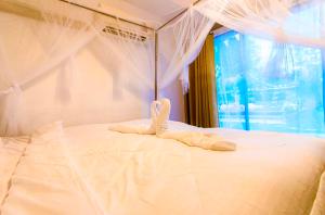 Ban Song Phi Nongบ้านสวีทคาบาน่า และบ้านสวีทโอโซนBy The mountain Ozone บ้านโอโซนขุนเขาแก่งกกระจาน的一张白色的床,上面有一条毛巾