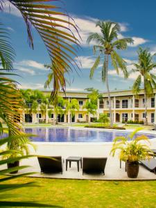 邦劳马利纳文度假酒店的一座带椅子和棕榈树的游泳池,位于一座建筑前