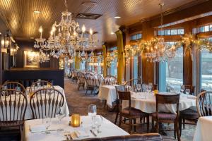 明尼阿波利斯Nicollet Island Inn的一间设有白色桌子和吊灯的用餐室