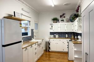 黄金海岸Beach House 100ms to Beach Freshly Renovated All New Appliances的厨房配有白色橱柜和白色冰箱。