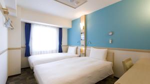 SodegauraToyoko Inn Sodegaura eki Kita guchi的酒店客房设有两张床和窗户。