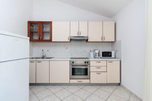 洛帕Apartments Marija P Lopar的厨房配有白色橱柜和炉灶烤箱。