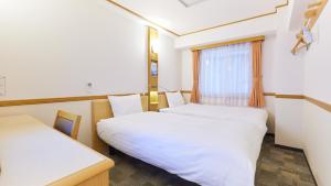 盛冈Toyoko Inn Morioka Ekimae的客房设有两张床和窗户。