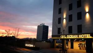 釜山Busan Myeongji Ciel Ocean Hotel的日落时在大楼前的酒店标志