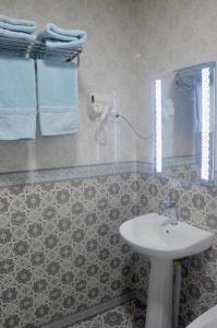 希瓦Guest House Dilorom的浴室配有水槽和带蓝色毛巾的淋浴