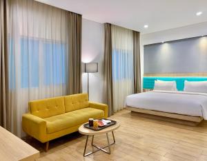 雅加达珊迪卡卡拉巴加丁酒店的酒店客房设有床和黄色沙发