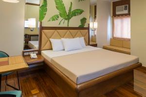 马尼拉Kabayan Hotel Pasay的一间卧室配有一张床、一张书桌和一张书桌
