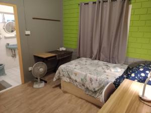 曼谷年轻美丽旅馆的一间卧室配有一张床和一张带风扇的书桌