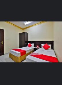 麦地那ريتاج الفضية للوحدات السكنية的客房内的两张床和红色枕头