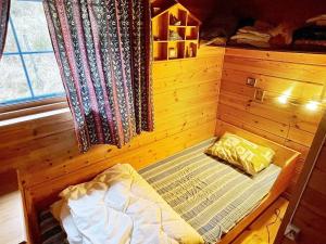 KyrpingThree-Bedroom Holiday home in Åkra的木制客房的一张小床,设有窗户