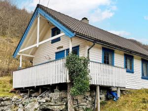 KyrpingThree-Bedroom Holiday home in Åkra的山坡上一座蓝色屋顶的房子