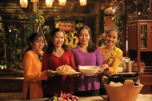 芹苴Vamxang Rustic Home的四个妇女站在一个厨房里,拿着一盘食物